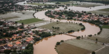 Vista aérea de uma cidade brasileira severamente alagada após eventos extremos de chuva.