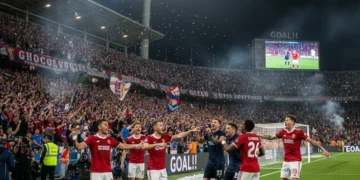 Estádio lotado com torcedores vibrantes, celebrando um gol e mostrando o poder da torcida.
