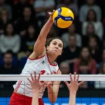 Novas Regras do Vôlei: Estratégias e Dinâmica de Jogo Jogador de vôlei atacando a bola sobre a rede em uma partida intensa.